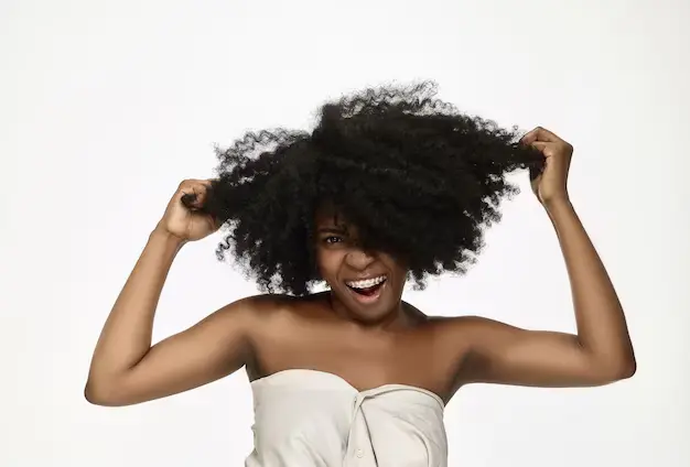a-black-woman-smiling-and-stretching-her-natural-hair